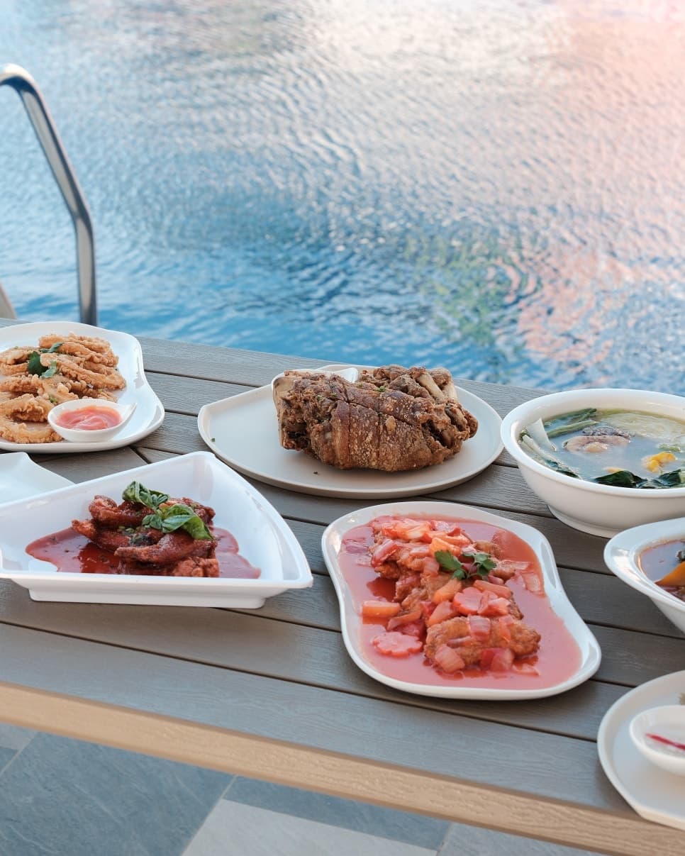 Crispy pata and kare-kare Filipino dishes served poolside at Merry Plates Restaurant Batangas